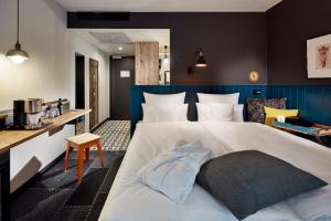- une chambre avec un grand lit blanc et une tête de lit bleue dans l'établissement me and all hotel Mainz, part of JdV by Hyatt, à Mayence