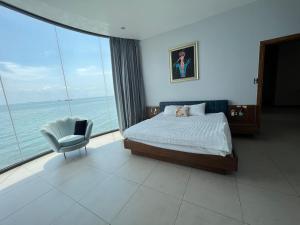 ein Schlafzimmer mit einem Bett und einem Stuhl sowie das Meer in der Unterkunft Nancy Tran Grand Strip Vung Tau Villa 9 in Vũng Tàu