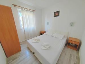 a bedroom with a large white bed and a window at Apartment Zvonko in Stara Novalja