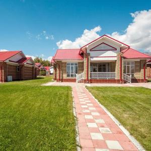 uma casa com um telhado vermelho e um jardim de relva em Отель Евразия em Cholpon-Ata