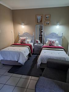 una camera d'albergo con due letti e una sedia di At Home BB a Estcourt