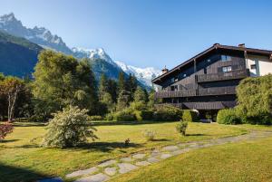 une maison dans un champ avec des montagnes en arrière-plan dans l'établissement Apartment Chapeau, Mont Blanc View, Alpes Travel, à Chamonix-Mont-Blanc