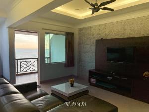 a living room with a couch and a flat screen tv at The Corus Suites Port Dickson By MAISON in Port Dickson