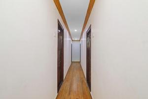 a hallway with white walls and wooden doors at Guest Inn Near Hyderabad Central in Hyderabad