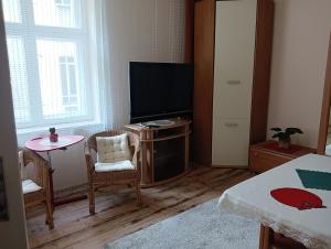 1 dormitorio con TV, mesa y cama en Oficynka, en Strzelce Opolskie