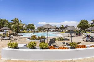a resort with a pool with chairs and umbrellas at Holyhome mills 1113 in Costa Teguise