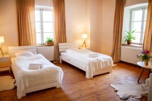 two beds in a room with two windows at Mooste Viinavabriku Hotell & Restoran in Mooste