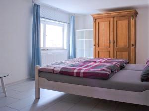 a bedroom with a bed with a wooden cabinet and a window at Ferienwohnung Die Schmiede in Schopfloch