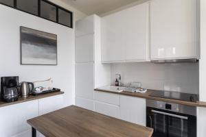 une cuisine avec des placards blancs et une table en bois dans l'établissement Le Rez de Plage - Appt pour 4 vue mer et proche des plages, à Saint-Malo
