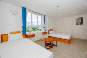 1 dormitorio con 2 camas, mesa y ventana en Light House Phú Quốc en Phu Quoc