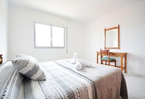 ein weißes Schlafzimmer mit einem Bett und einem Spiegel in der Unterkunft Apartamento Vistas Vilar in Sanxenxo