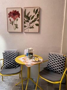 a table and two chairs with a yellow table and two paintings at Studio Dageraad in Antwerp
