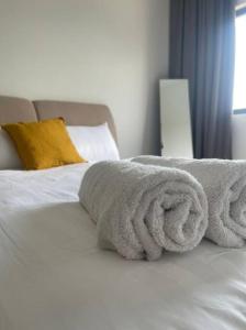 un letto bianco con due asciugamani sopra di Sunway Gandaria 3BR Full AC w/ Pool Wi-Fi Netflix a Bandar Baru Bangi