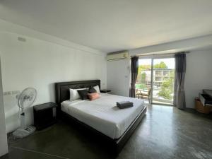 a bedroom with a bed with a fan and a window at Spacious Apartment by the Sea in Bangrak Beach
