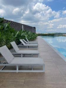 a row of lounge chairs sitting next to a swimming pool at Sunway Gandaria 3BR Full AC w/ Pool Wi-Fi Netflix in Bandar Baru Bangi