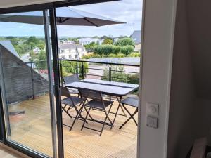 balcón con mesa, sillas y sombrilla en Appartement lumineux avec terrasse !, en Plonéour-Lanvern