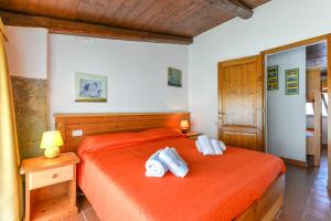 sypialnia z pomarańczowym łóżkiem i ręcznikami w obiekcie 12 Amiata Mountain Charm Pool, Fast Wi-Fi, Free Parking w mieście Castel del Piano +39 zdjęć
