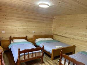two beds in a room with wooden walls at Lazer Cardaku guest house in Valbonë