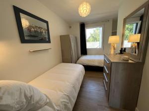 a bedroom with two beds and a dresser and a refrigerator at Bénodet: appartement avec terrasse, proche plage, thalasso et restaurants - FR-1-481-147 in Bénodet