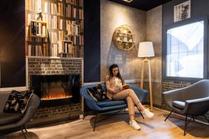 a woman sitting in a chair in a living room with a fireplace at ibis budget Paris Porte de Vanves in Vanves