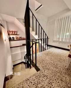 una escalera en una casa con una barandilla negra en 鳳米宿Roomi house3, en Tainan