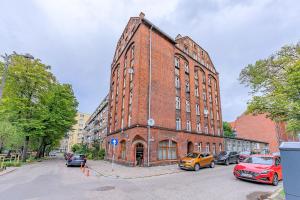 a red brick building with cars parked in front of it at Apartament Przytulny z 2 sypialniami na Starym Mieście/ 2bedrooms Old Town in Gdańsk