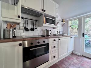 a kitchen with white cabinets and a stove top oven at Cosy Weavers Cottage - Heart of Frome in Frome