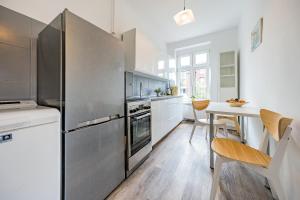 a kitchen with a stainless steel refrigerator and a table at Apartament Przytulny z 2 sypialniami na Starym Mieście/ 2bedrooms Old Town in Gdańsk