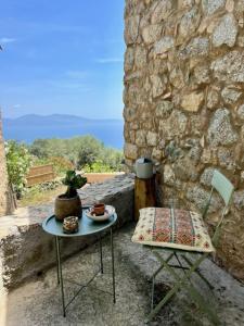 una mesa y una silla junto a una pared de piedra en charmante bergerie à Cargese tres belle vue mer avec jardin en Cargèse