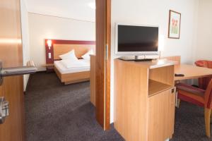 a room with a television on a desk with a bed at Hotel Restaurant JÄGERHAUS in Meckenbeuren