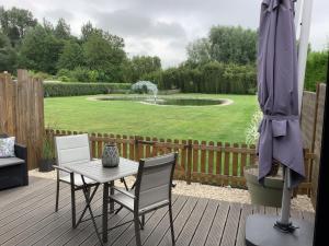 a patio with a table and chairs and a pond at Gite Ni vu ni connu in Guînes