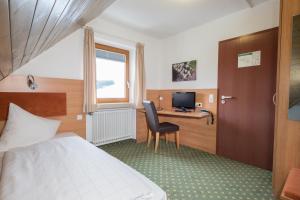 ein Hotelzimmer mit einem Bett und einem Schreibtisch mit einem Computer in der Unterkunft Hotel Jägerhaus in Meckenbeuren