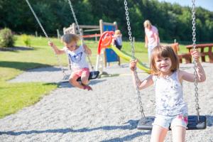 two little girls sitting on swings at a playground at Hotel Restaurant JÄGERHAUS in Meckenbeuren +35 photos