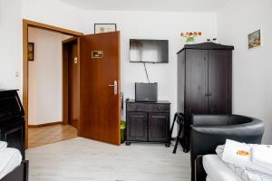 a living room with a couch and a tv and a door at Ruhige Zimmer im Grünen in Berlin