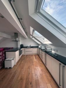 a large kitchen with white cabinets and a large window at Seascape Penthouse with Free Parking in Plymouth