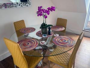 Seascape Penthouse with Free Parking في بلايموث: طاولة زجاجية مع كراسي و مزهرية مع الزهور الأرجوانية