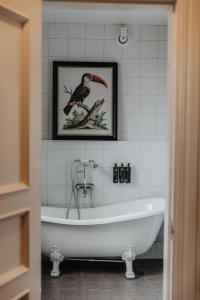 baño con bañera y una foto de un pájaro en Hotel Slottsvillan en Huskvarna