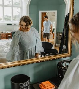 een vrouw die voor een spiegel staat bij Hotel Slottsvillan in Huskvarna