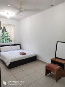 a bedroom with a bed and a table and a window at TulipVilla Homestay in Kampong Parit