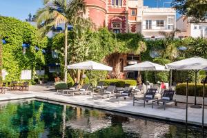 a pool with chairs and umbrellas next to a building at Hotel Medium Sitges Park in Sitges