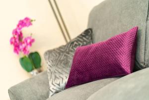 a purple pillow on a gray couch with a vase of flowers at Rosemount Residence - SJA Stays in Aberdeen