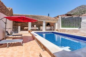 una piscina con una sombrilla roja junto a una casa en Casa Juan y Loli en Nigüelas