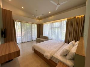 ein Schlafzimmer mit einem großen Bett und großen Fenstern in der Unterkunft Oceanature Alibaug in Alibag
