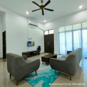 a living room with couches and a ceiling fan at Rumah Pantai de Merabang (bungalow with pool) in Bachok