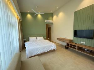 a bedroom with a bed and a flat screen tv at Oceanature Alibaug in Alibaug