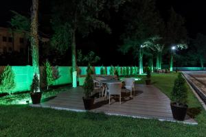 una terraza de madera con mesa y sillas por la noche en Gelati Residence en Kutaisi