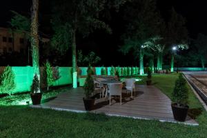 a wooden deck with a table and chairs at night at Gelati Residence in Kutaisi