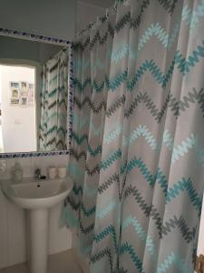uma casa de banho com um lavatório e uma cortina de chuveiro em Islantilla - Bajo con Jardín en Golf Islantilla em Huelva