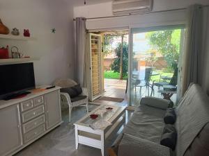 sala de estar con sofá y TV en Islantilla - Bajo con Jardín en Golf Islantilla en Huelva