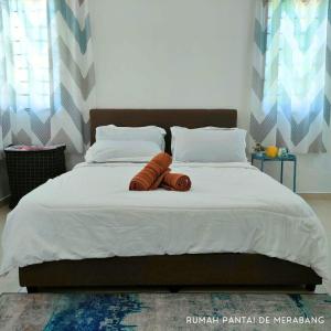 een slaapkamer met een groot bed en 2 bruine dekens bij Rumah Pantai de Merabang (bungalow with pool) in Bachok